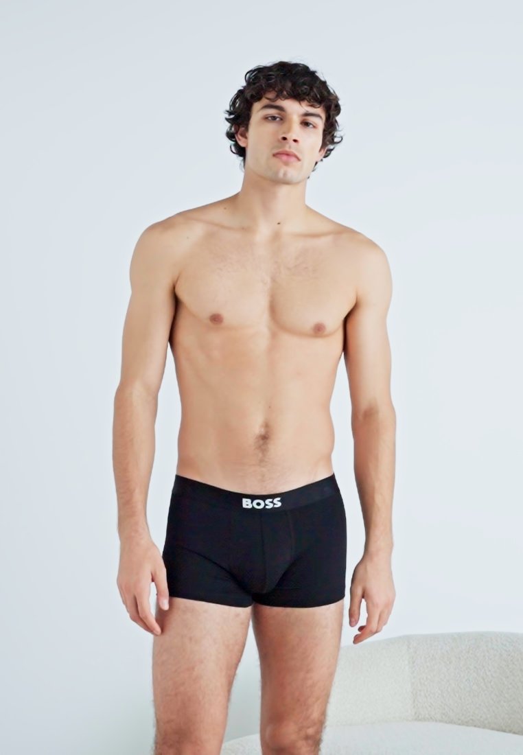Boxer-briefs noirs avec le logo "BOSS" en blanc sur la ceinture élastique, fabriqués à partir d'un matériau lisse et extensible, s'ajustant près du corps.