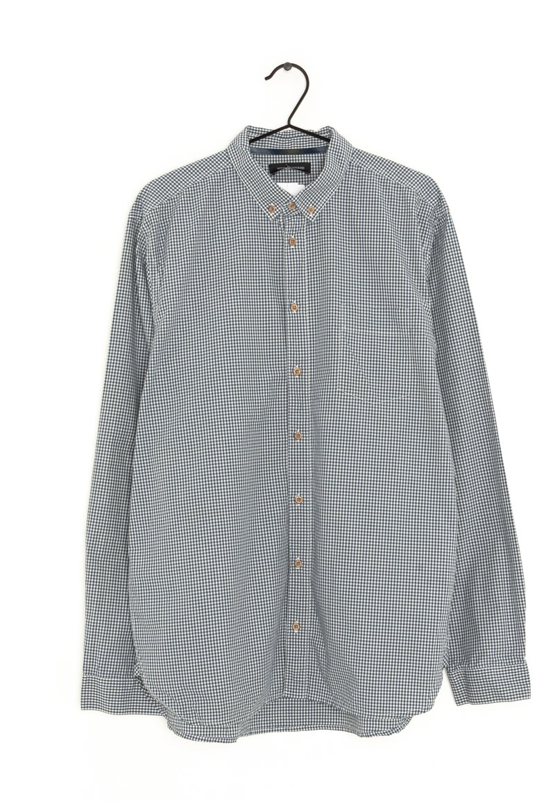 Chemise à manches longues à carreaux bleus navy et blancs, avec un col et une poche plaquée sur la poitrine.