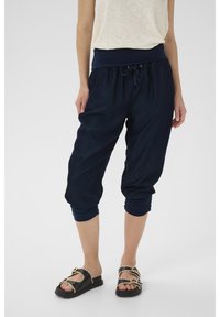 Pantaloni cropped leggeri di colore blu navy con vita elasticizzata e cordoncino. Tessuto morbido, polsini svasati e vestibilità ampia per il massimo comfort.