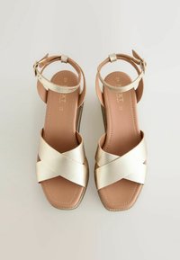 Sandales métalliques dorées à lanières avec une finition texturée, design croisé et semelle intérieure rembourrée couleur tan. Bride de cheville réglable et petit talon.