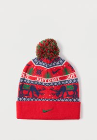 Κόκκινο πλεκτό σκουφάκι με σκούρο μπλε και λευκό σχέδιο νιφάδας χιονιού, πράσινες λεπτομέρειες και πράσινη φούντα στην κορυφή. Εμφανίζει το κείμενο "JUST DO IT" και το λογότυπο της Nike.