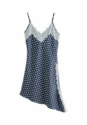 Marineblauwe satijnen slipjurk met witte polka dots, witte kanten afwerking langs de halslijn, zij-split en dunne schouderbandjes.