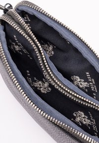 Pochette grigia con zip in tessuto, dotata di una zip argentata, con un interno in tessuto blu e una stampa del logo nera sulla fodera interna.