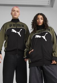 Melni un olīvzaļi sporta jakas ar rāvējslēdzēju priekšpusē, ar baltu Puma logo un akcentu detaļām. Klāt riboti piedurkņu gali un apakša.