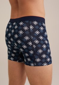 Tengerészkék boxer alsó, fehér és kék hópehely mintával. Puha derékpánttal és kényelmes, testhezálló kialakítással rendelkezik.