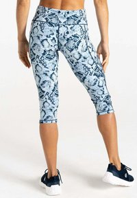 Leggings capri de estampado de serpiente en azul y blanco, con una cintura alta, que presentan una textura suave y un diseño ajustado. Combinadas con zapatos deportivos negros.