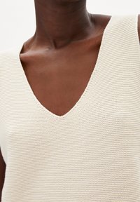 Hihaton kerma neulepaita V-kaula-aukolla, teksturoidulla kankaalla, jossa vaakasuorat raidat, ja siististi viimeistellyt reunat.