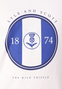 Baltas medvilninis marškinėliai su mėlynu apvaliu logotipu. Centriniame dizaino elemente pavaizduotas erškėtis, skaičiai "18" ir "74", o viršuje užrašas "LYLE AND SCOTT", o apačioje "THE WILD THISTLE".