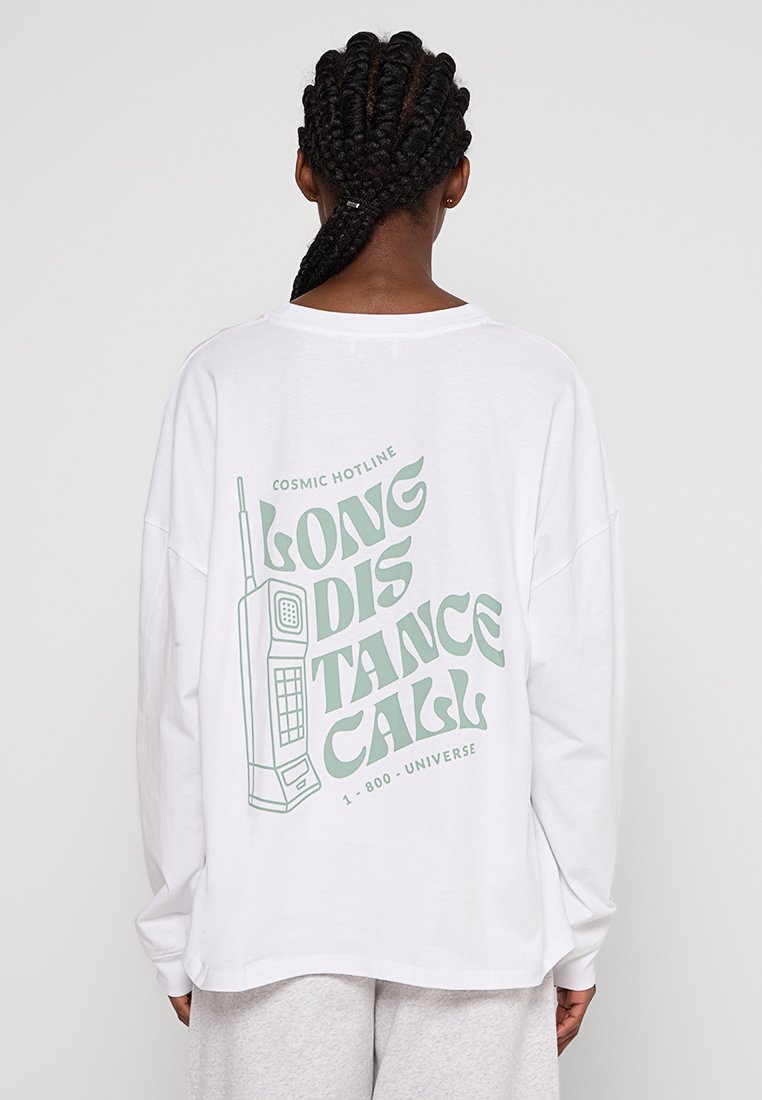 Weißes Langarm-T-Shirt mit einem Retro-Telefonzellen-Graphic in grün, versehen mit den Texten "LONG DISTANCE CALL" und "COSMIC HOTLINE."