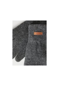 Gants en laine tricotés gris avec des poignets côtelés. Présente une petite étiquette en cuir marron avec "BARTS" embossé. Texture douce.