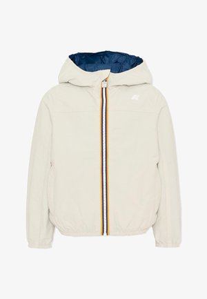 Veste beige à capuche avec poignets élastiques, fermeture éclair rayée multicolore et doublure intérieure bleu foncé.