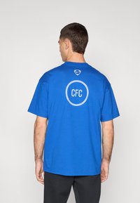 Blå bomulds T-shirt med et rundt "CFC" logo og Nike swoosh design på ryggen. Korte ærmer og en afslappet pasform.
