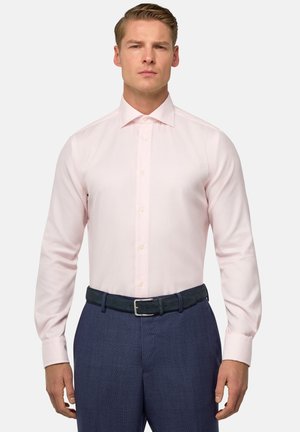 Lichtroze overhemdd met een gestructureerd patroon, met knoopkraag en lange mouwen, gecombineerd met donkerblauwe broek en riem.