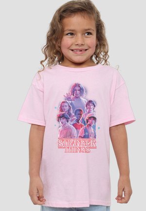 Rosa Baumwoll-T-Shirt mit einem grafischen Druck, der mehrere Charaktere aus "Stranger Things" in verschiedenen Posen und Gesichtsausdrücken zeigt.