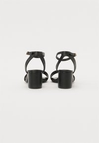 Sandali neri con tacco a blocco, cinturino regolabile e apertura sul retro. Realizzati in pelle liscia con un design minimale e senza motivi visibili.