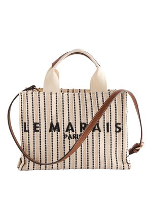 Płócienna torba na ramię z pionowymi czarnymi paskami, wyszywanym napisem "LE MARAIS PARIS", krótkimi białymi uchwytami oraz długim, brązowym regulowanym paskiem na ramię.
