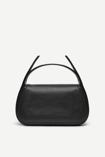 Sac à main en cuir noir de forme rectangulaire incurvée avec de larges anses doubles sur un fond uni.