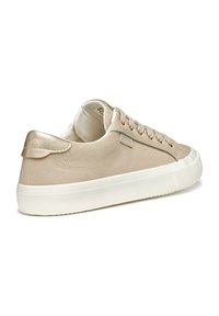 Beige lerret sneakers med en myk tekstur, metalliske detaljer og en hvit gummisåle. Har en logo og klassisk snøring.