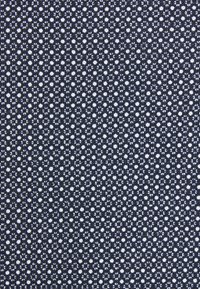 Motif dense de petits points blancs sur un tissu texturé sombre, espacés uniformément et constants sur toute la surface.