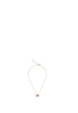 Collier en plaqué or avec une chaîne fine et un petit pendentif décoratif rouge et blanc. Design simple avec un fermoir ajustable.