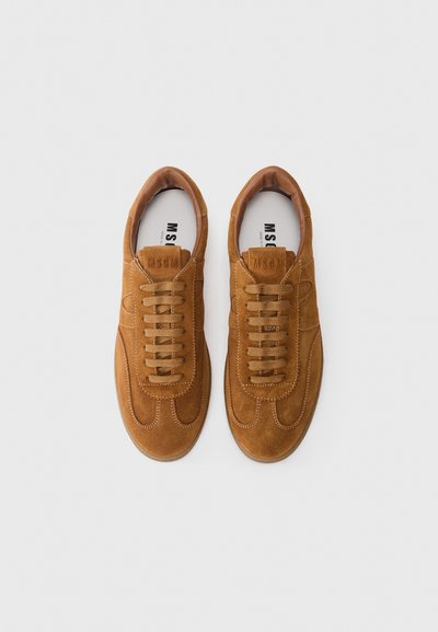 Sneaker in suede beige con punta arrotondata, superficie testurizzata e lacci abbinati. Presenta un'etichetta con logo sulla linguetta e dettagli di cucitura in contrasto.