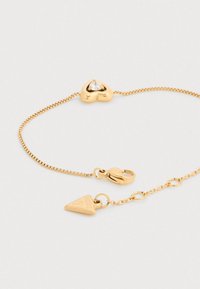 Χρυσό βραχιόλι με γοητεία σε σχήμα καρδιάς που διαθέτει διαφανές πολύτιμο λίθο, αλυσίδα με υφή και τρίγωνο κρεμαστό μενταγιόν.