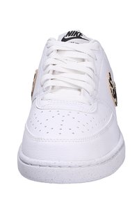 White leather athletic shoe with perforated toe, flat laces, and a distinctive black and beige logo on the side. Textured rubber outsole.