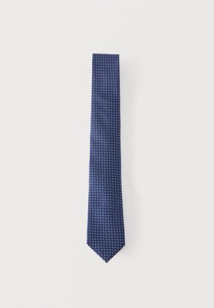 Cravate bleu marine avec un petit motif géométrique blanc, posée à plat sur un fond neutre.