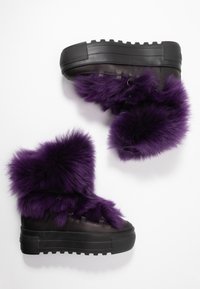 Fialové kotníkové boty z umělé kožešiny s tlustou černou platformou, obsahující hladký kožený základ a smyčkované tkaničky na zapínání.