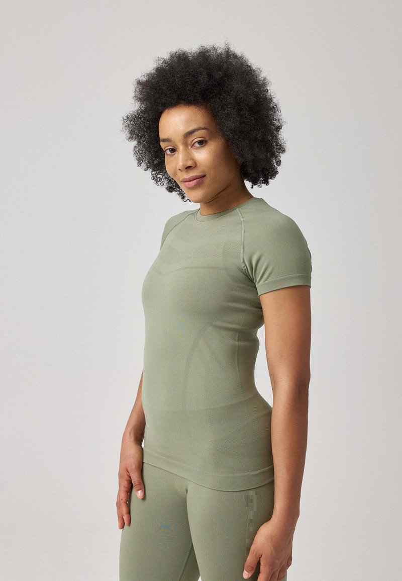 Top sportivo fitted a maniche corte di colore verde chiaro, realizzato in tessuto elasticizzato con righe testurizzate. Abbinato a leggings coordinati.
