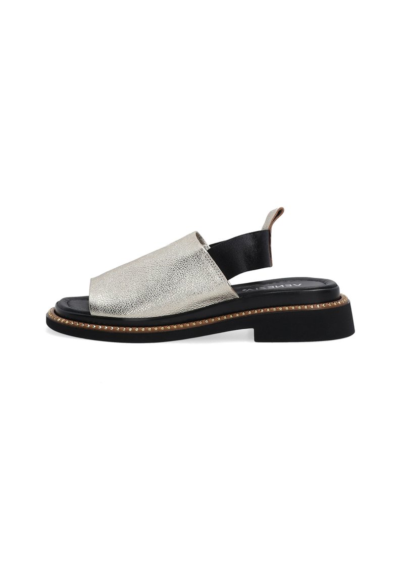 Metallic sølv åben tå sandal med en sort elastisk rem, tekstureret overdel og en kraftig sort sål med dekorativ stikning.