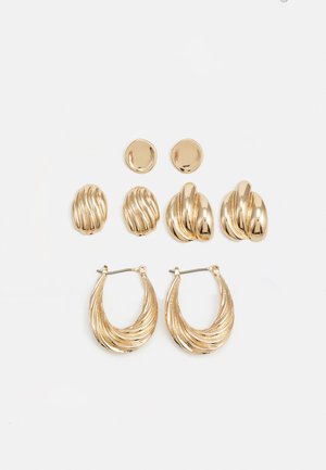 Ensemble de boucles d'oreilles dorées comprenant trois paires : des clous ovales texturés, des clous au design ondulé et de grandes boucles d'oreilles avec des nervures superposées.