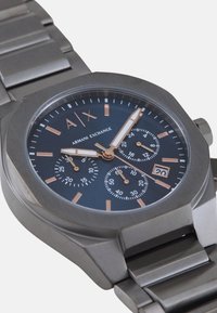 Satničnjak od nehrđajućeg čelika s osmostranim kućištem, mornarskom plavom brojčaniku, detaljima od ružičastog zlata, sub-brojčanicima i prikazom datuma, s narukvicom od karika.