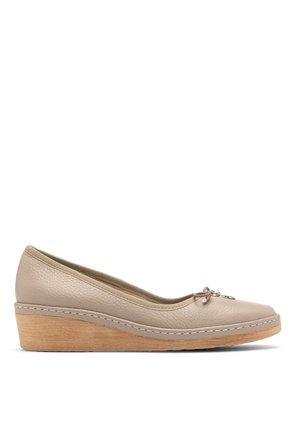 Beige nahkalenkkari, joka on pyöreähuippuinen, tekstuuripinta ja koristeellisia nauhoja, joissa on pieni charmipitsi edessä. Vaalea puinen korko.
