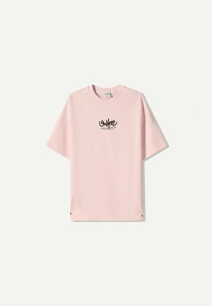 T-shirt rose clair avec un col rond et des manches courtes. Texte de logo noir imprimé sur le devant. Présente une coupe décontractée et une texture en coton doux.