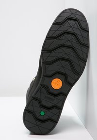 Suola di scarpa in gomma nera con un motivo a zigzag. Presenta accenti in gomma arancione e verde, contrassegnati con la scritta "Sensorflex".