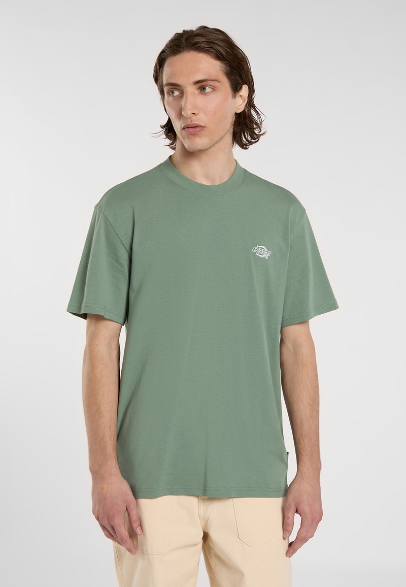 Grøn t-shirt med korte ærmer lavet af blødt bomuld. Har en rund halsudskæring og et lille logo nær venstre bryst. Glat tekstur, afslappet pasform.