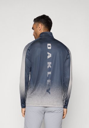 Navy long-sleeve quarter-zip top with gradient gray design. Features "OAKLEY" logo in large text on the back, smooth texture, and fitted style.