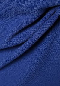 Texturiertes blaues Gewebe mit einem gewebten Muster, das subtile Drapierungen aufweist. Das Material scheint leicht und weich im Griff zu sein, mit einer glatten Oberfläche.