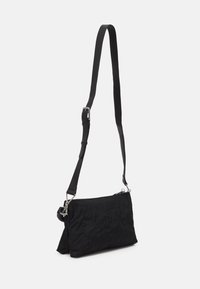 Schwarze gesteppte Umhängetasche mit rechteckiger Form, verstellbarem Riemen und silbernen Hardware-Elementen. Strukturierte Oberfläche mit Blumenmuster.