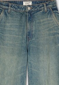 Jeans in denim azzurro chiaro con taglio dritto, dotati di chiusura con bottone, passanti per cintura e cuciture a contrasto. L'etichetta mostra la taglia e i dettagli del marchio.