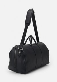 Black leather duffel bag with a zip closure, dual handles, and a detachable black fabric strap. Features silver hardware accents.