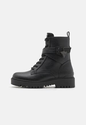 Stivaletti neri alla caviglia realizzati in pelle testurizzata, con punta rotonda, design con lacci, dettaglio con cinturino e fibbia, e suola in gomma spessa.