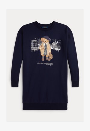 Navy Sweatshirt mit einem Grafikum eines Teddybären in einem beigen Mantel, mit braunen Schuhen und einem Hut. Der Hintergrund zeigt illustrierte Gebäude.