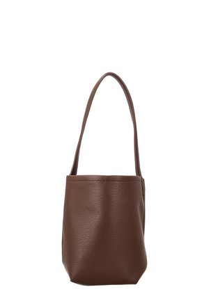 Bruine leren bucketbag met één lange riem, gladde getextureerde oppervlakte en minimalistisch design tegen een witte achtergrond.