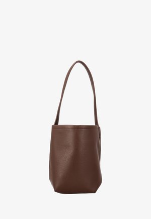Bruine leren bucketbag met één lange riem, gladde getextureerde oppervlakte en minimalistisch design tegen een witte achtergrond.