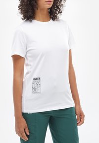 T-shirt blanc à manches courtes en coton avec un col rond et une étiquette graphique noire sur le côté gauche. Texture lisse.