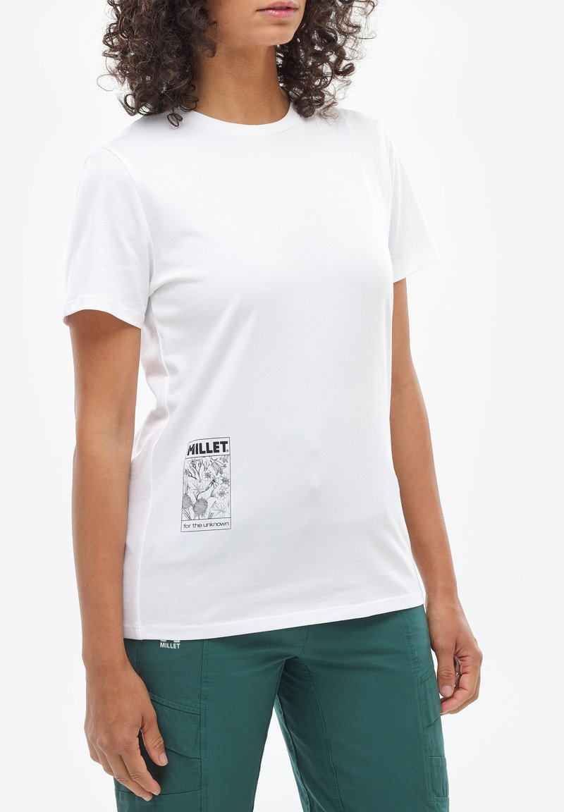 T-shirt blanc à manches courtes en coton avec un col rond et une étiquette graphique noire sur le côté gauche. Texture lisse.