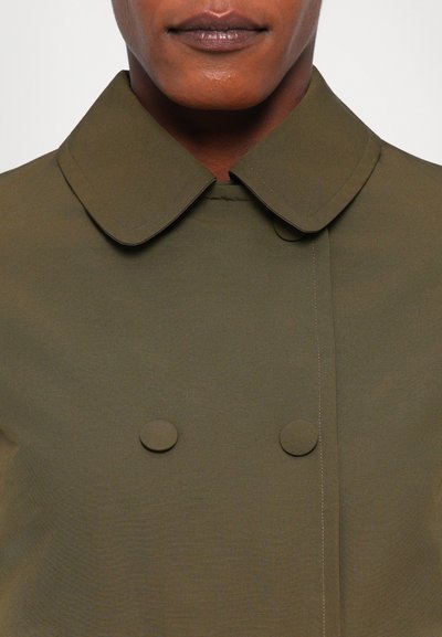 Palton verde olive cu un design cu două rânduri de nasturi, guler rotund și două nasturi rotunzi, realizat dintr-un material neted și texturat.