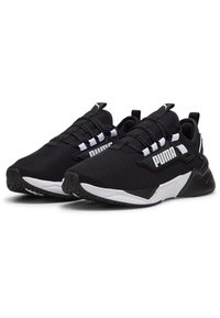 Zapatillas deportivas negras con parte superior de malla, con un logotipo blanco prominente, diseño de cordones y una suela blanca y negra en contraste.